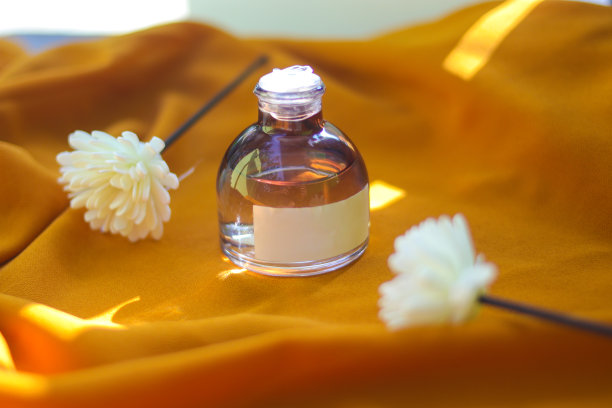 香水瓶与空白白色标签纹理橙色织物背景。香水瓶库存照片图片下载