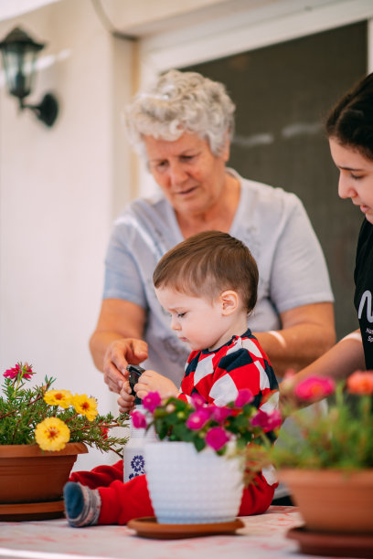 小男孩和姐姐、奶奶在阳台上浇花图片下载