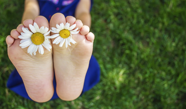 孩子们的脚与甘菊在绿色的草地上。有选择性的重点。图片下载