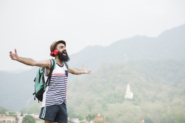 年轻的大胡子男子听音乐在山车站:-库存照片图片下载