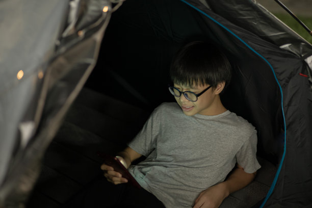 亚洲少年男孩上网使用电话在后院营地图片下载