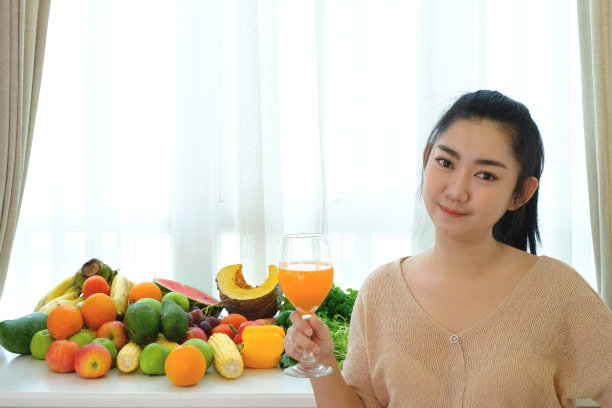 肖像妇女手握新鲜榨橙汁在玻璃杯与各种新鲜成熟的水果和蔬菜图片下载