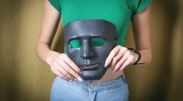 拿着黑色面具的年轻女子。假的,匿名图片下载