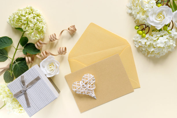 米色桌子上放着白色绣球花束的礼品盒，节日贺卡，附邀请函或祝贺信的信封图片下载