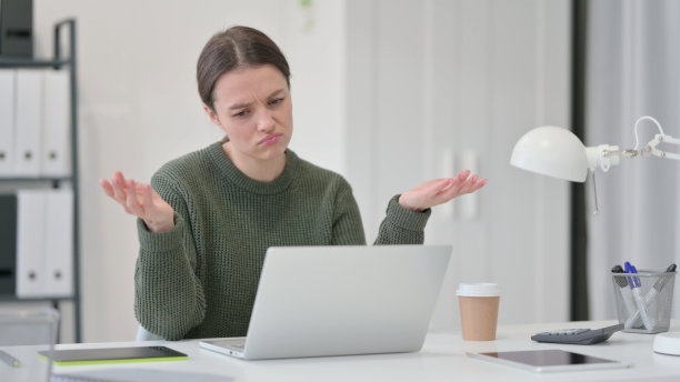 拿着笔记本电脑的年轻女子对失去的反应图片下载