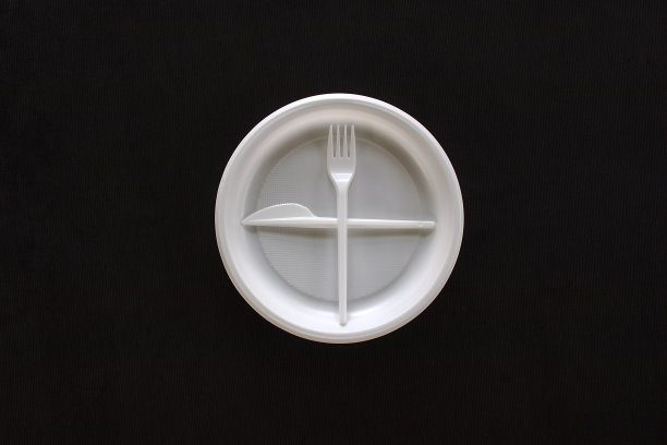 一次性白色塑料盘、叉和刀放在黑色天鹅绒上。从以上观点。礼仪规则。图片下载