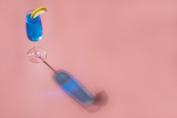 粉色背景上的蓝色鸡尾酒配上强烈的灯光和阴影图片下载