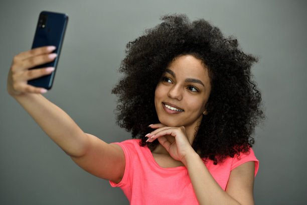 年轻漂亮的黑人女性在用智能手机自拍。图片下载
