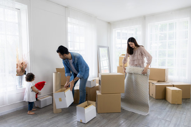 这家人刚搬到新家。整理物品有许多包裹盒子。父母和孩子在一起组织事情时很开心。图片下载