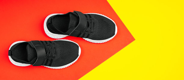黑色时尚运动鞋。黑色的鞋子上的彩色背景红与黄，广告照片。图片下载