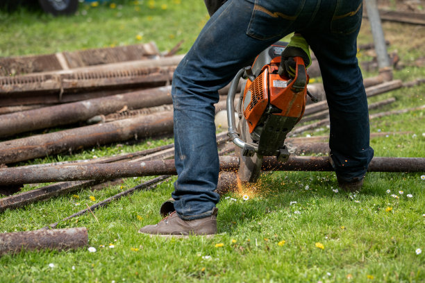 工人用圆锯锯金属管道和废料。火花和火焰图片下载