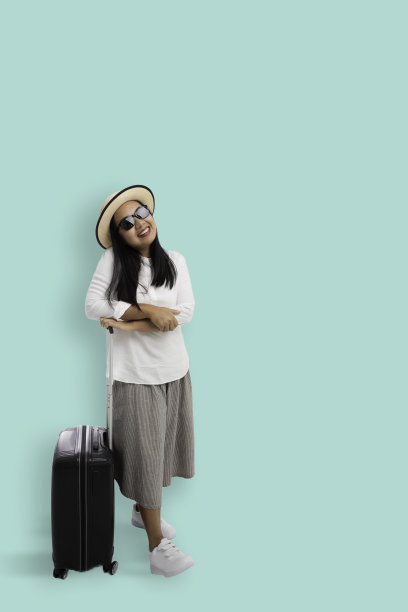 女游客的肖像在休闲与太阳眼镜微笑站与旅行行李孤立的背景，夏季旅游概念，垂直拍摄图片下载
