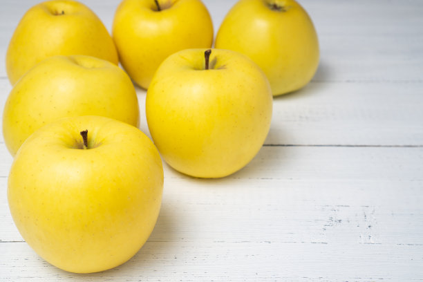 漂亮的黄熟金苹果在白色的木桌上。甜美多汁的水果。图片下载