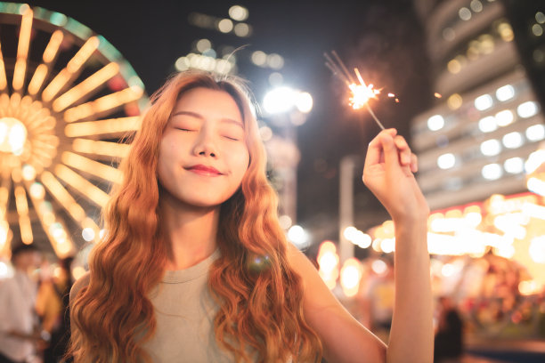 快乐的女孩正在一个公共游乐场用她的手机拍照。美丽微笑的游客女人在一个游乐园在炎热的夏天一天旅行泰国曼谷夜生活。图片下载