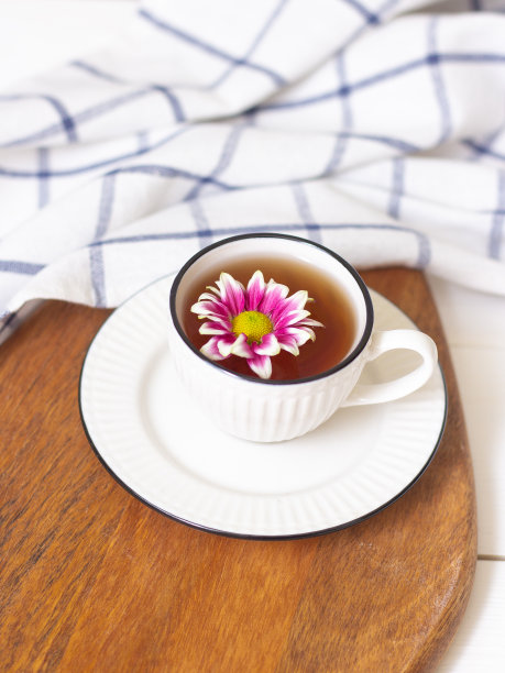一杯茶和一朵花。木托盘上放着一个杯子，一条格子毛巾。春天的概念。温柔和女性气质。图片下载