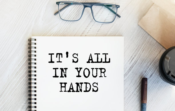 写着“一切尽在你手中”的记事本。装着咖啡的纸杯，桌上还有装着早餐的纸袋。从以上观点。市场营销的概念。图片下载