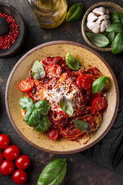 意大利面与蕃茄酱，西红柿，奶酪和罗勒在一个黑暗的背景俯视图，垂直照片图片下载