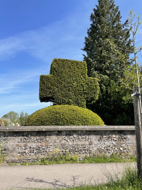 修剪成十字形的紫杉树篱，小路旁石墙后的教堂墓地，宗教象征，阳光灿烂的日子图片下载