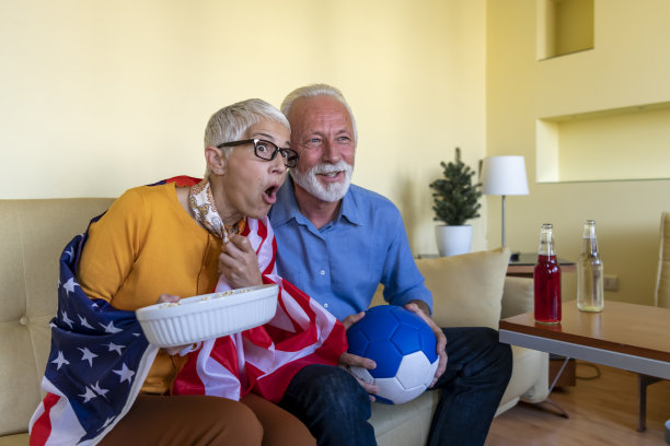 一位老人和他的妻子正在看一场足球赛，他们都支持美国国家队。图片下载