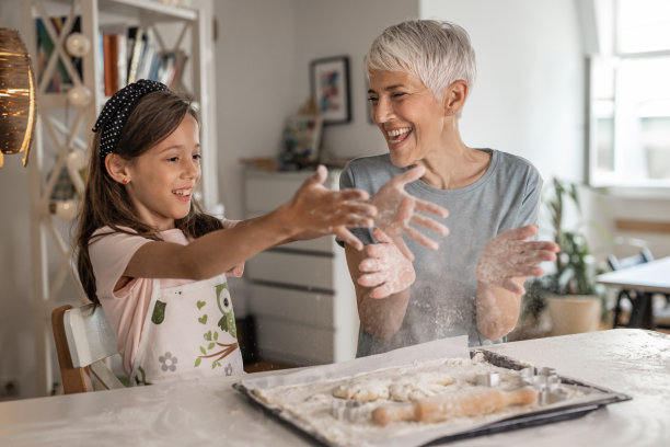 年长的女人和年轻的女孩在烘焙和玩乐图片下载