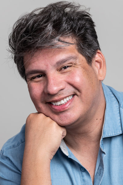 微笑的成熟男子看着灰色背景的相机图片下载