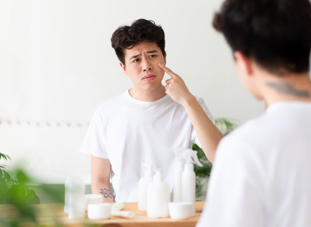 沮丧的亚洲千禧一代的家伙在白色t恤触摸脸，不高兴与炎症图片下载