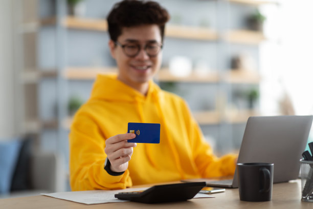 微笑的亚洲人在家里展示信用卡图片下载