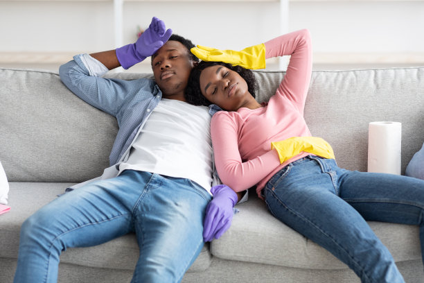 疲惫的非裔美国男人和女人打扫完公寓后休息图片下载