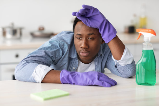 疲惫的黑人戴着手套拿着喷雾器和海绵图片下载