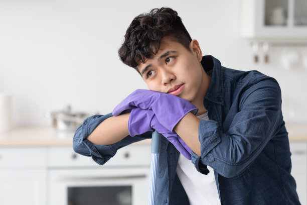 疲惫的亚洲人靠在扫帚上，看着复印空间图片下载