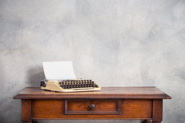 老式打字机和空白纸在复古木制桌子前混凝土墙背景。复古风格滤镜照片图片下载