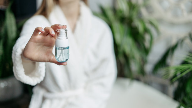 穿着浴袍的年轻女子在镜头前展示装有化妆品的瓶子图片下载