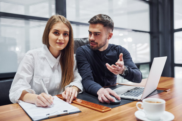 女人和男人的肖像，穿着正式的衣服，在室内的办公室靠桌子图片下载