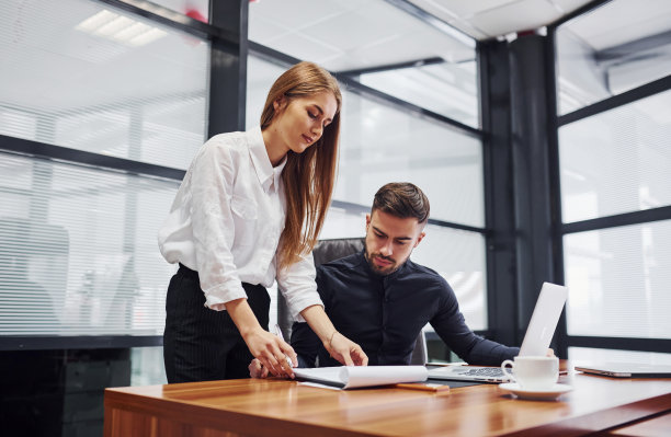 女人和男人穿着正式的衣服一起在室内的办公室靠桌子工作图片下载