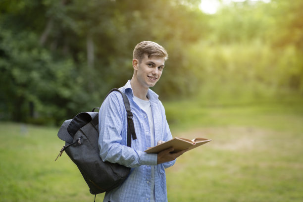 十几岁的大学生拿着书在校园里摆姿势图片下载