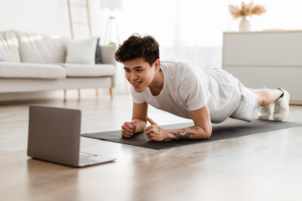 运动亚洲男人做平板支撑看教程上的笔记本电脑图片下载