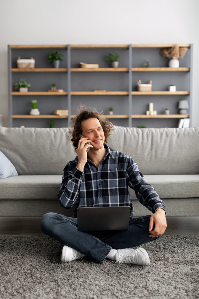 男性自由职业者坐在家里用笔记本电脑打电话图片下载