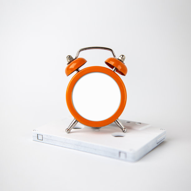 一个橙色的模拟闹钟位于一个白色录音带。时钟以白色背景添加内容。图片下载