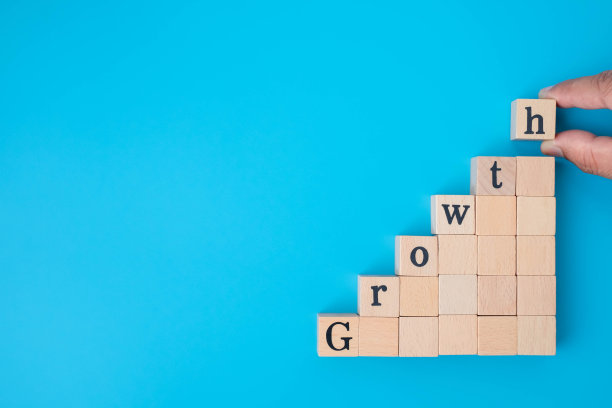 手工安排的木方块与字增长堆叠作为楼梯上的蓝色背景。企业投资与财务会计概念为成长成功过程提供复制空间。图片下载