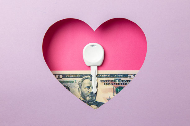 这把钥匙和50美元的钞票在紫色的背景上有一颗粉红色的心。图片下载