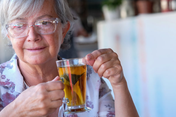 美丽的老妇人在咖啡厅，享受花草茶的肖像。位头发花白的人图片下载