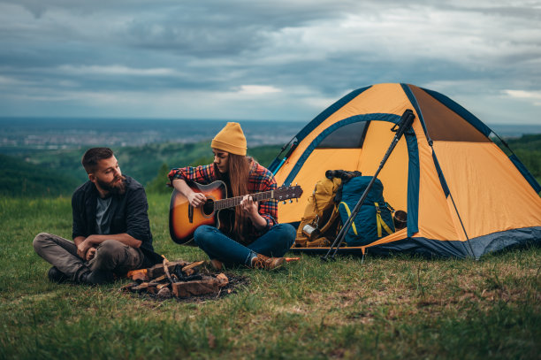 几个露营者坐在帐篷附近弹吉他图片下载