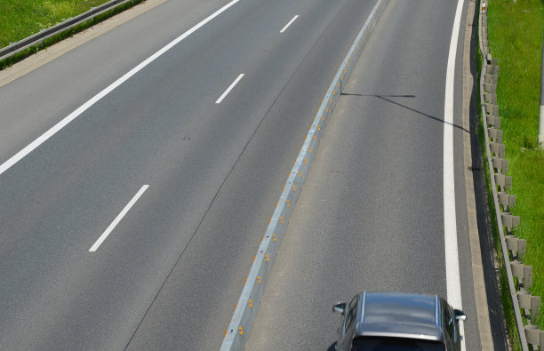 水平道路标志车道。公路上有混凝土护栏。车辆碰撞车道分隔符。黄色带黑色条纹。指示橙色闪光方向的光锥图片下载