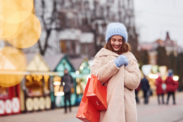 年轻女孩穿着暖和的衣服，手里拿着购物袋在城市的户外散步图片下载