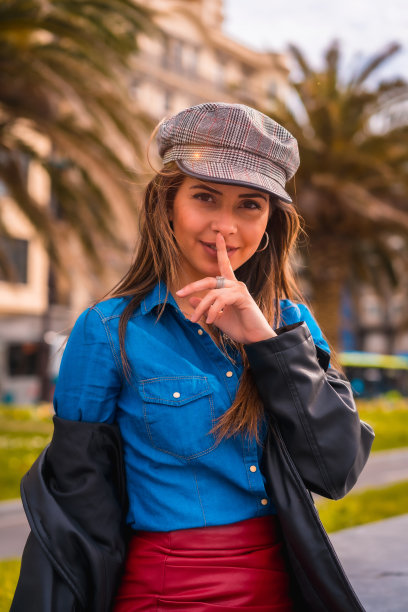 城市的生活方式，一个漂亮的黑发白种人坐在牛仔衬衫，贝雷帽和红色短裙坐着享受暑假图片下载