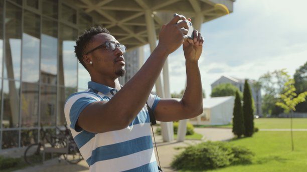一名游客在外面用手机拍照。年轻的非洲裔美国人在街上用手机拍照。图片下载