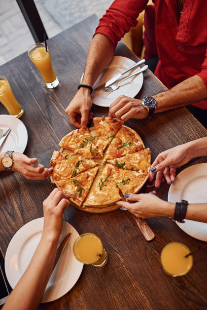 近距离观察人们在室内一起吃披萨图片下载
