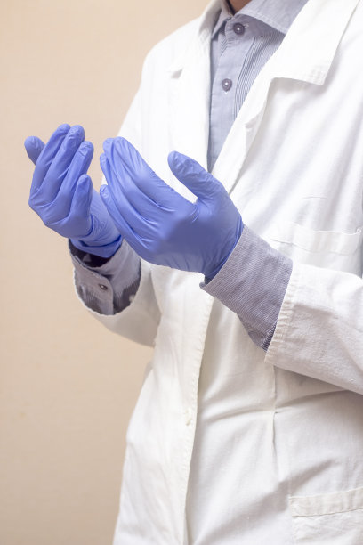 一个身穿白大褂的年轻人举起双手，开始祈祷。医用手套。米色背景。医生正在祈祷。穆斯林做dua。图片下载