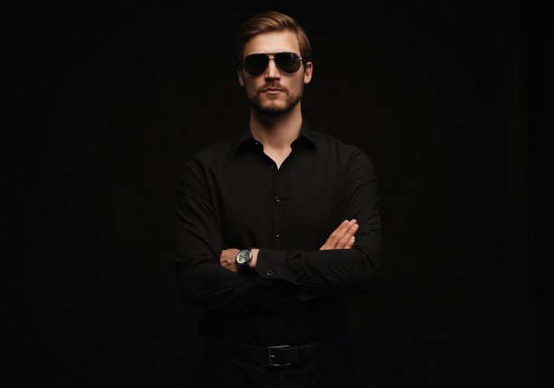 穿着全套西装的男人。自信的年轻商人戴着墨镜孤立地站在黑色。图片下载