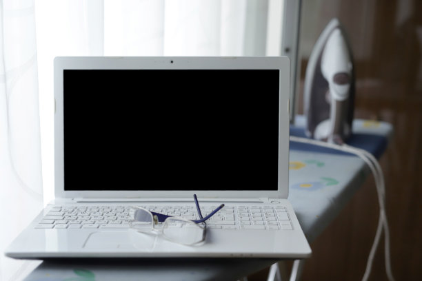 把笔记本电脑和眼镜放在熨衣板上图片下载